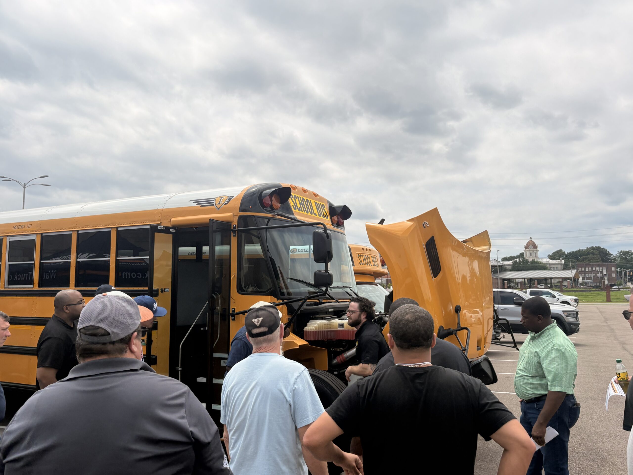 Technicians examining a school bus engine at the MAPT trade show